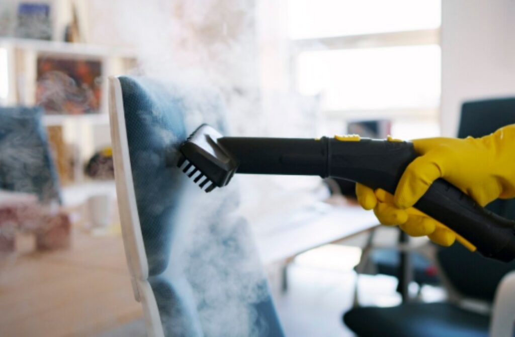Persona con guantes amarillos limpiando muebles con un limpiador a vapor en Cartagena, mostrando frescura y limpieza profesional.