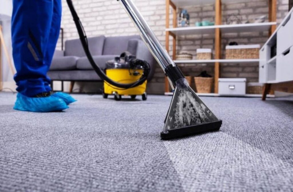 Persona limpiando una alfombra con una aspiradora en un servicio profesional a domicilio en Manizales.