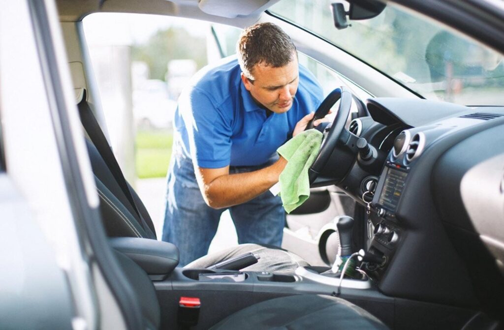 Hombre limpiando el interior de un coche en Bucaramanga, mostrando un detalle profesional en el servicio de lavado.