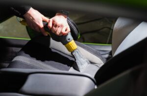 Persona aspirando el asiento de un auto durante un servicio de lavado interior en Cartagena. Higiene total garantizada