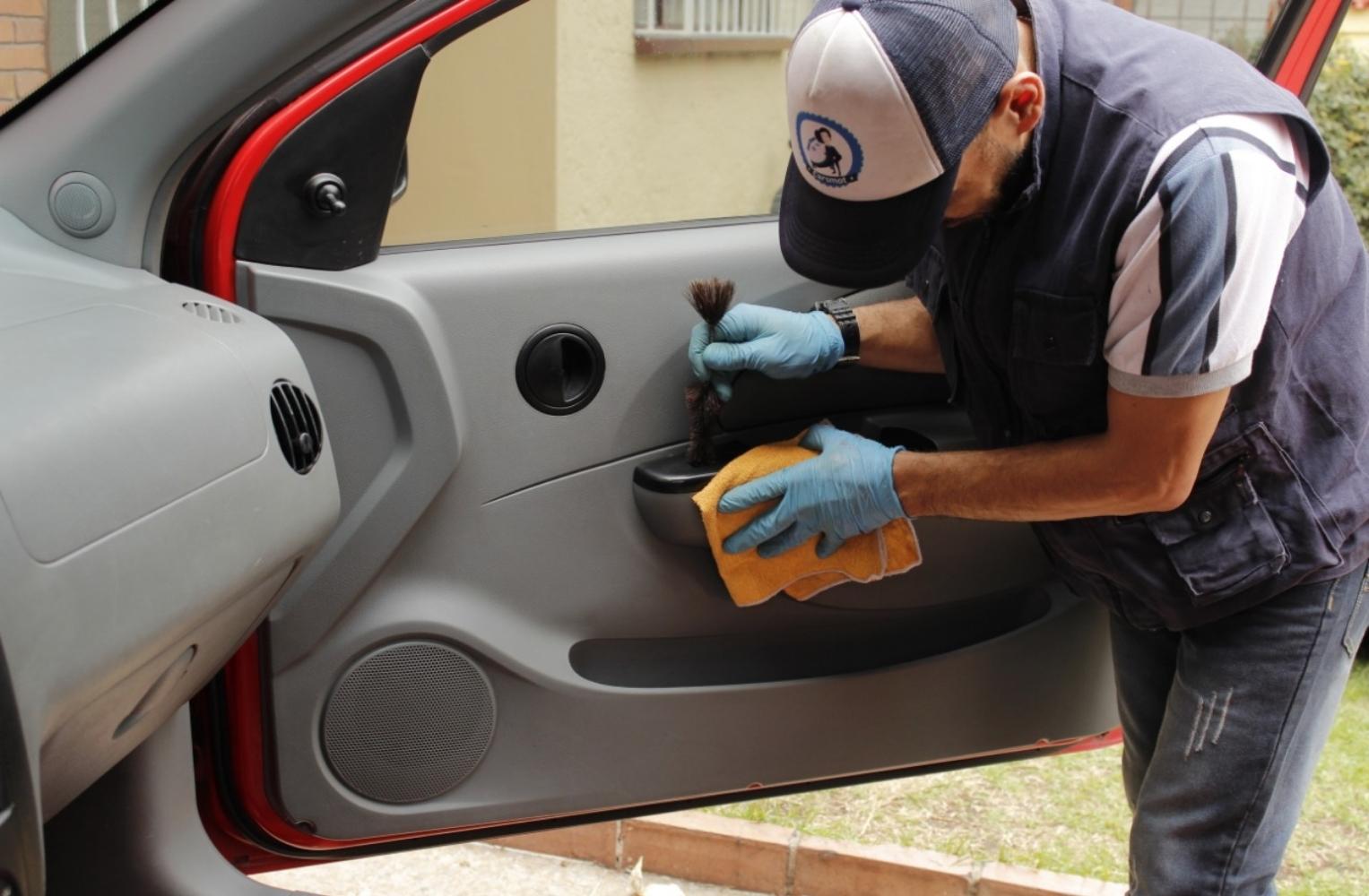 Hombre limpiando el pomo de una puerta de auto en Cartagena, promoviendo la higiene total en el lavado de vehículos.